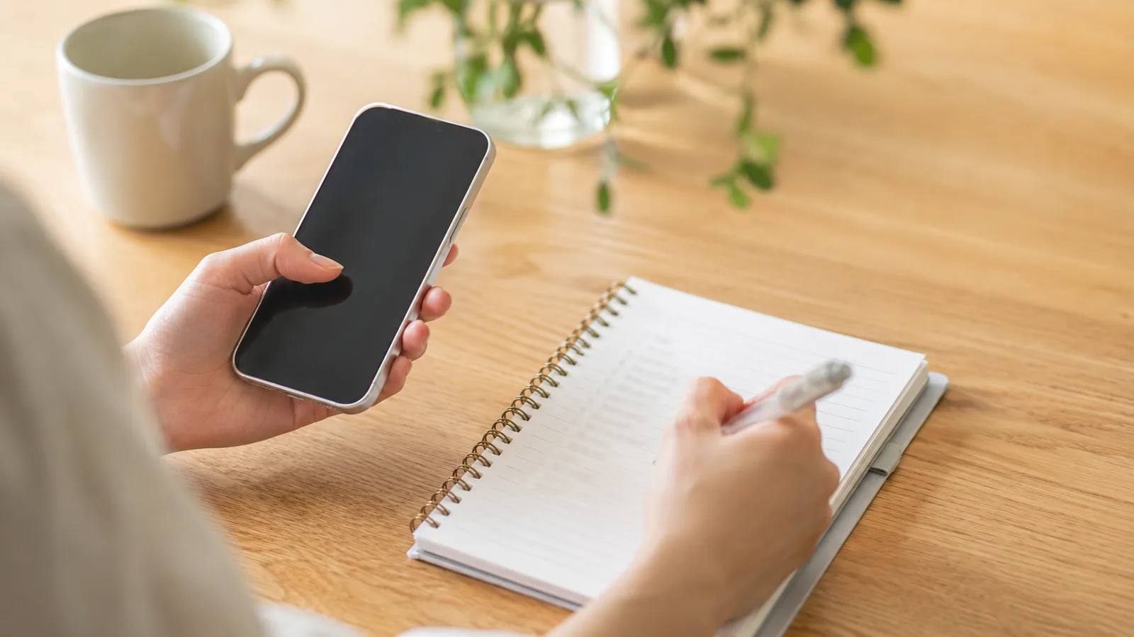 スマホを見ながら、登録しているサービスをノートに書き出して一覧を作っている手元