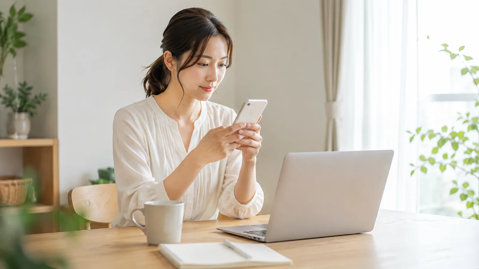 ダイニングテーブルでスマホとパソコンを使い、会員登録しているサービスを整理する女性