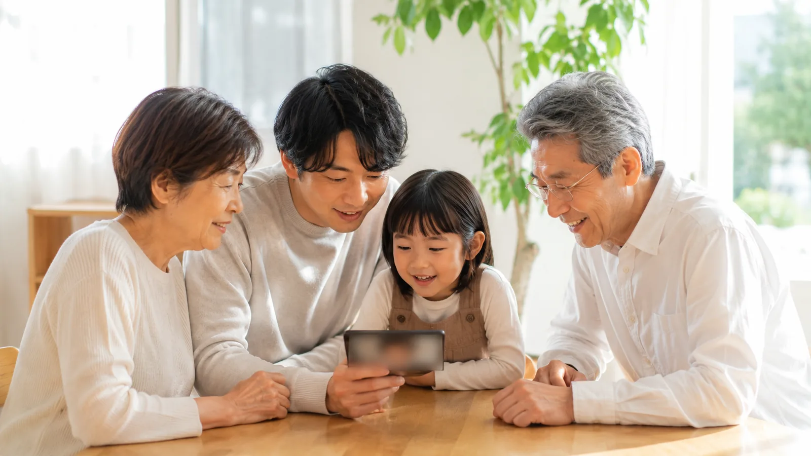 スマートフォンの写真を三世代の家族で一緒に見て笑い合う様子