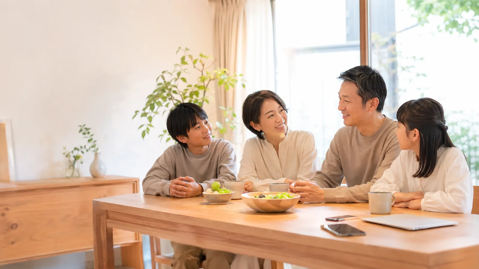 ダイニングで穏やかに会話する家族。整理したデジタル情報を家族と共有できている安心のイメージ