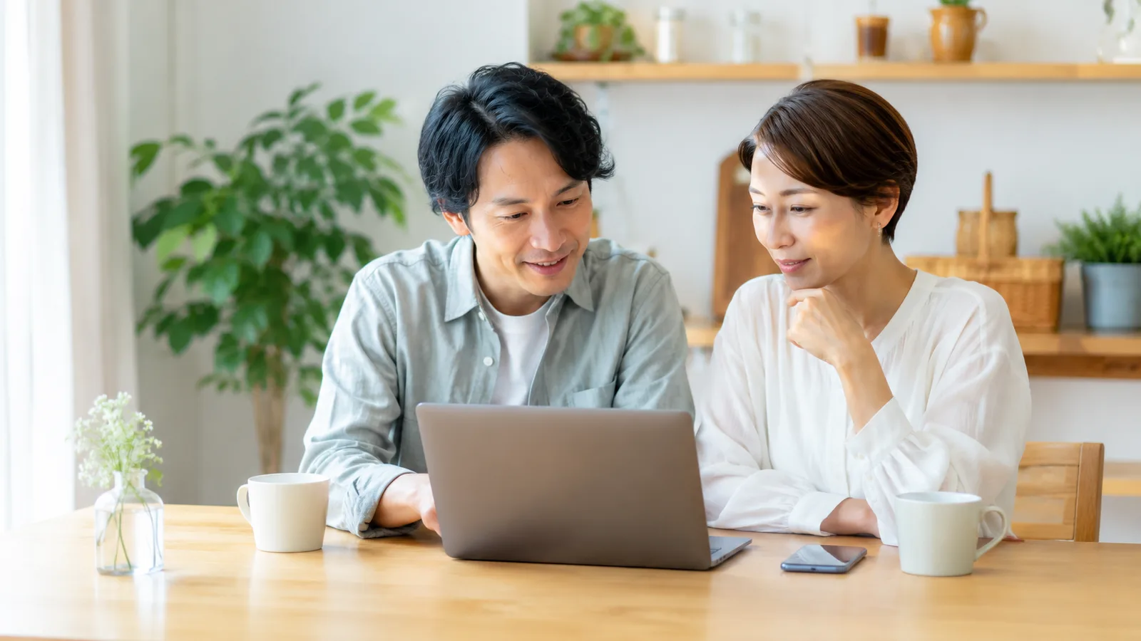 ダイニングで夫婦が一緒にパソコンを見ながら、穏やかにお金の話をしている様子